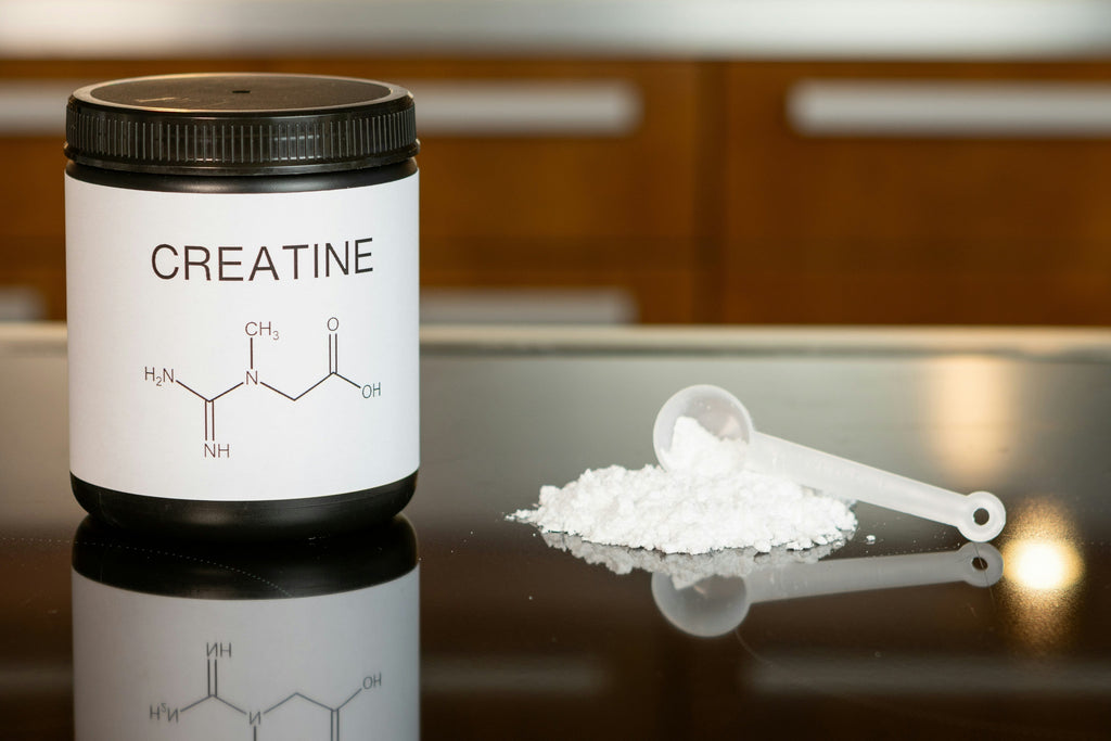 Creatine monohydrate canister and a scoop of powder on a table