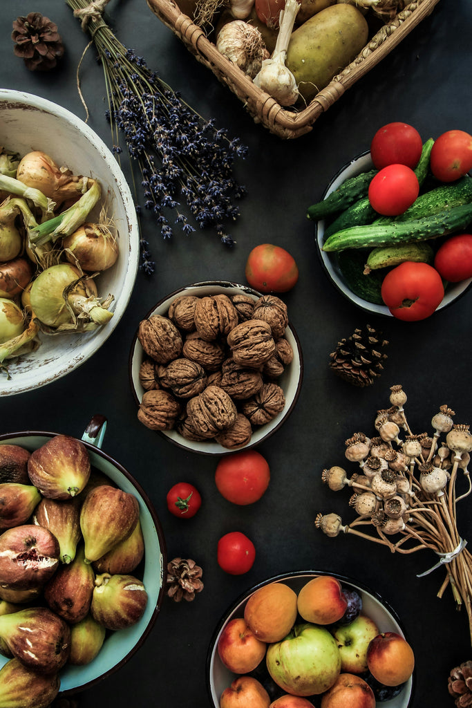 various nuts, fruits, dates, mushrooms, vegetables, berries in bowls and displayed flat on a table, overhead view
